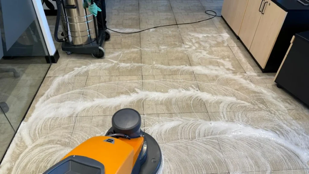 Equipo de limpieza profesional de pisos, mostrando la tecnología TASKI y la aspiradora industrial recuperando agua sucia para resultados óptimos.