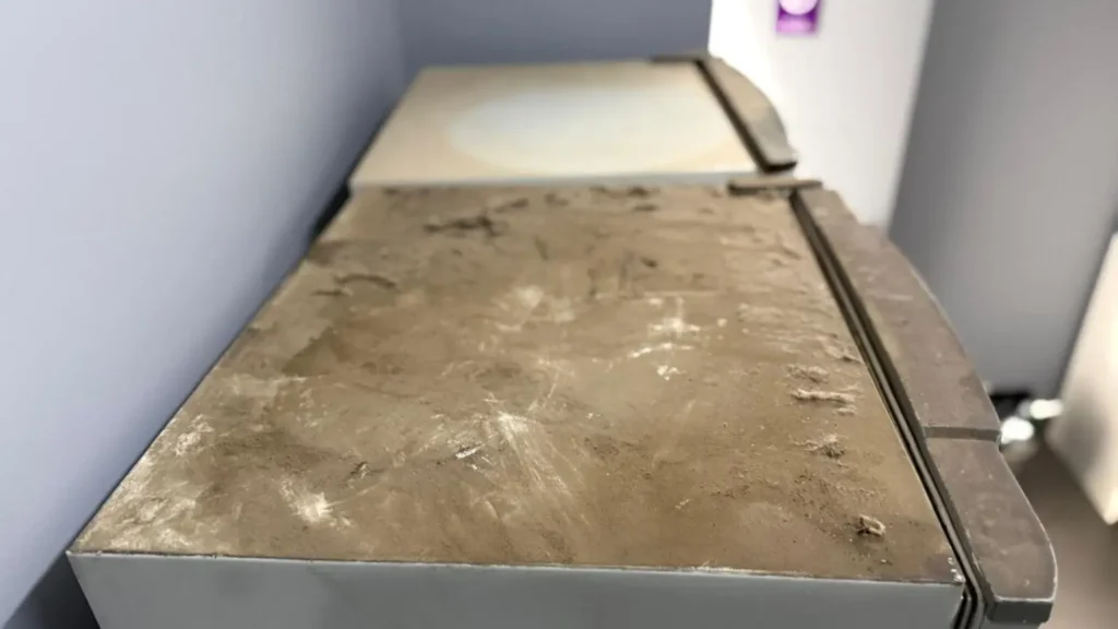 Parte superior de un refrigerador corporativo con extrema acumulación de polvo y suciedad, antes de la limpieza.